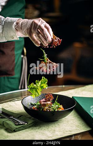 Koch bereitet Salat mit Eisberg in einer Gourmet-Schüssel zu Stockfoto