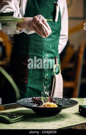 Koch bereitet Salat mit Parmesan in einer Gourmet-Schüssel zu Stockfoto