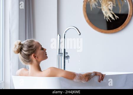 Junge Frau, die zu Hause mit Schaum baden Stockfoto