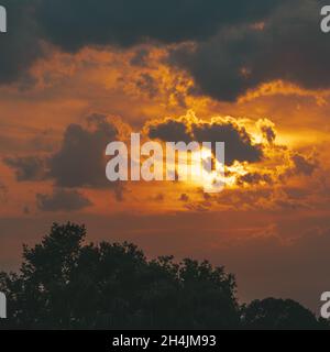 Wolken am Himmel mit dem Sonnenlicht, das beim Sonnenuntergang durch sie kommt Stockfoto