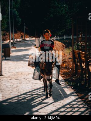 Kleiner Dorfjunge, der auf einem Esel reitet Stockfoto