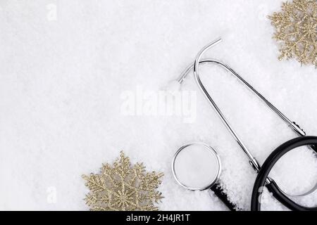 Medizinisches Stethoskop auf einem verschneiten Hintergrund in der Nähe von Schneeflocken. Medizinisches Konzept für Weihnachten oder Neujahr. Flach. Speicherplatz kopieren Stockfoto