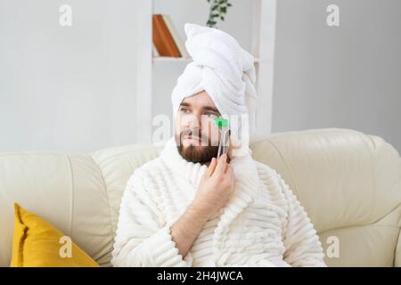 Bärtiger Mann mit Gesichtsmassage-Werkzeug. Männliches Hautpflege- und Spa-Konzept. Stockfoto