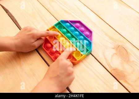 Nahaufnahme der Kinderhände, die mit dem farbenfrohen „Pop IT Fidget“-Spielzeug spielen. Anti-Stress. Beliebte entspannende Rhomben Form Silikon Stress Relief Spielzeug. Spiele für Stockfoto