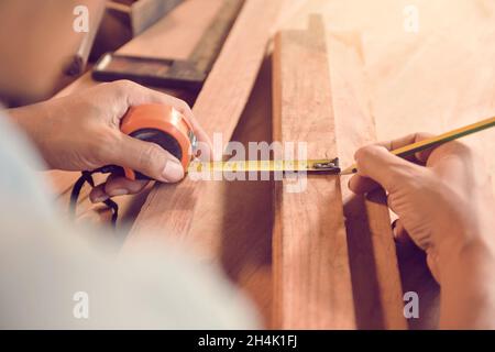 Zimmermann, der in seiner Werkstatt ein Stück Holz misst Stockfoto