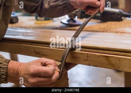 Nahaufnahme der Tischlerhand mit einem manuellen Hobel auf Holz Stockfoto