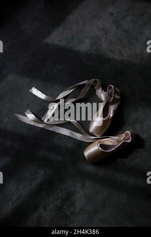 Blick von oben auf ein Paar rosa Ballettschuhe auf dem Boden bei Sonnenlicht Stockfoto