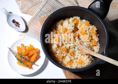 Köstliches Kürbisrisotto mit frischem Thymian und Parmesan in einem Topf. Italienische Küche. Direkt darüber. Stockfoto