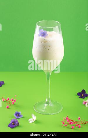 Milchshake weißer Cocktail im Glas mit Beeren und Blumen Stockfoto