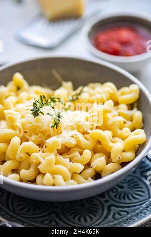 Schüssel Cavatappi Pasta mit geriebenem Parmesan und einer Schüssel Tomatensauce Stockfoto