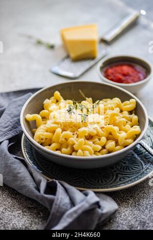 Schüssel Cavatappi Pasta mit geriebenem Parmesan und einer Schüssel Tomatensauce Stockfoto