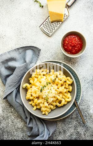 Schüssel Cavatappi Pasta mit geriebenem Parmesan und einer Schüssel Tomatensauce Stockfoto