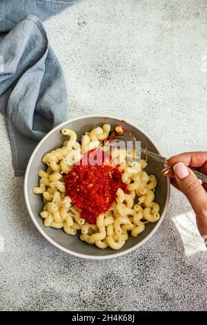 Frau, die eine Schüssel Cavatappi-Pasta mit Tomatensauce und geriebenem Parmesan isst Stockfoto