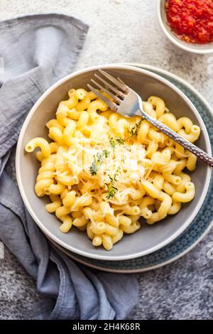 Schüssel Cavatappi Pasta mit geriebenem Parmesan und einer Schüssel Tomatensauce Stockfoto