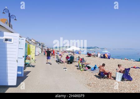 Familien am Strand mit Pop-up-Strandzelten Liegestühle Sonnenschirme und Paddle-Boards am Sandstrand bei Lyme Regis Dorset England GB Europa Stockfoto