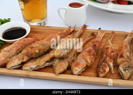 Holzplatte mit gebratenem roten Meerbarsch auf dem Esstisch Stockfoto