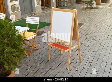 Im Sommer steht ein weißer, unbeschriftete Schild für das Straßencafé Stockfoto