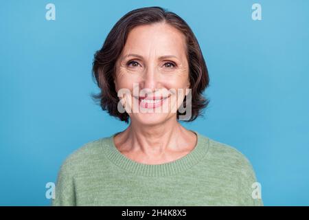 Porträt von attraktiven fröhlichen Inhalt grauhaarige Frau mittleren Alters tragen Pullover isoliert über lebendigen blauen Hintergrund Stockfoto
