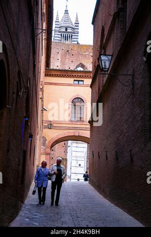 Romanischer Bogen und gestreifter gotischer Glockenturm der Kathedrale von Siena in Italien. Stockfoto