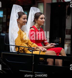 Zwei Frauen in Pferdekutsche tragen die typische spanische Mantilla und kämmen in einer Parade auf dem Fuengirola-Markt. Stockfoto