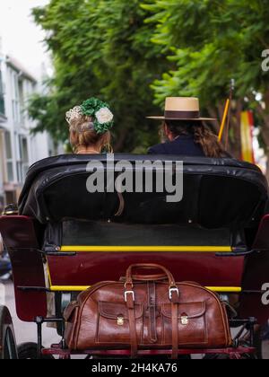 Rückansicht einer Familie in einer Pferdekutsche in typisch andalusischer Tracht, in einer Parade der Messe von Fuengirola. Stockfoto