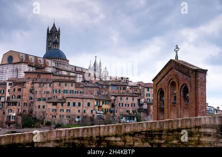 Drei Glocken in Siena, Italien, und der Kirchturm und die Kuppel der Kathedrale von Siena. Stockfoto