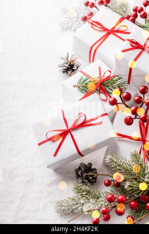 Weihnachtsgeschenkschachteln mit Dekorationen auf weißer Tischdecke. Stockfoto