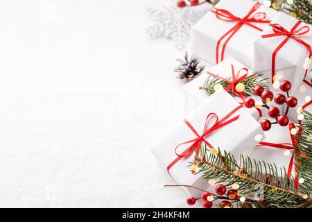 Weihnachts-Geschenkschachteln mit Dekorationen auf weißer Tischdecke mit Kopierfläche. Stockfoto