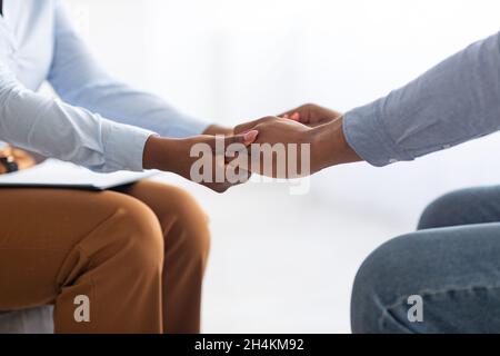 Professionelle Unterstützung. Psychotherapeut hilft gestressten männlichen Patienten, hält seine Hände in der psychiatrischen Klinik, Nahaufnahme. Unkenntlich Psychologe comforti Stockfoto