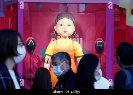 3. November 2021, Tokio, Japan: Fußgänger kommen an einer Nachbildung der „Younghee“-Puppe des südkoreanischen Netflix-Megahit-Dramas „Squid Game“ vor der Shibuya Station vorbei, einer der belebtesten Stationen der Welt. Die Statuen der Puppe und zwei Wachen in pinkfarbenen Uniformen sind im Einkaufsviertel von Shibuya installiert, wo die Menschen Fotos von der Puppe machen konnten, während sie der Stimme und der Musik des Spiels „Rotes Licht, grünes Licht“ lauschten. (Bild: © Rodrigo Reyes Marin/ZUMA Press Wire) Stockfoto