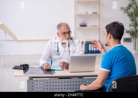 Junge Patientin besucht alten männlichen Arzt Stockfoto