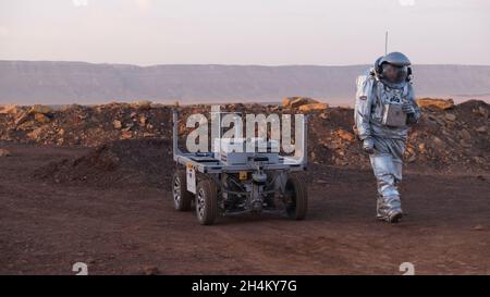 Ein analoger Astronaut, gekleidet in einen speziellen Raumanzügen, umläuft einen Rover auf dem Gelände der Mars-ähnlichen Forschungseinrichtung, die für die AMADEE-20-Mars-Simulation am Ramon-Krater in der Negev-Wüste in Israel gebaut wurde. Sechs Analogastronauten aus Israel, Portugal, Spanien, Deutschland, den Niederlanden und Österreich haben eine dreiwöchige Isolation innerhalb der Forschungseinrichtung abgeschlossen und konnten ihren Lebensraum nur in Raumanzügen verlassen. Das Team führte eine Reihe von wissenschaftlichen und technologischen Experimenten durch, in der Hoffnung, die Grundlagen für zukünftige bemannte Missionen zum Mars zu schaffen. Stockfoto