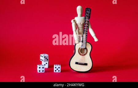 Auf einem roten Hintergrund ein Holzmann mit einer Gitarre in der Nähe von Würfel Stockfoto