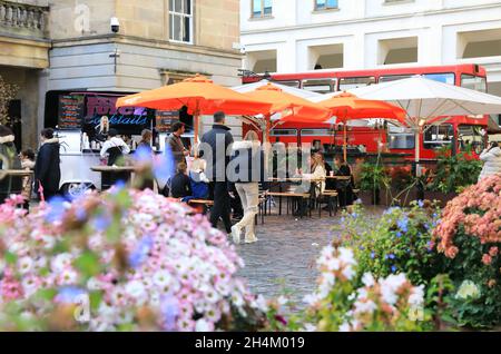 Menschen entspannen sich in Covent Garden, bei Herbstblumen, in London, Großbritannien Stockfoto