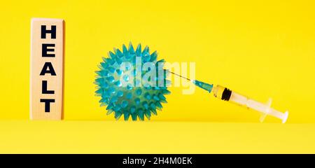 GESUNDHEITSTEXT aus Holzwürfel auf gelbem Hintergrund. Impfstoff und Virus. Stockfoto