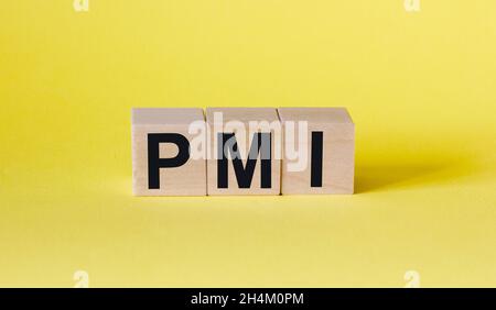 Das PMI-Wort besteht aus Holzbausteinen. Gelber Hintergrund .Geschäftskonzept Stockfoto