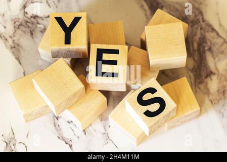 Das Wort ja steht in schwarzen Buchstaben auf Holzblöcken geschrieben. Meldung Ja auf hellem Hintergrund. Geschäfts-, Motivations- und Bildungskonzept Stockfoto