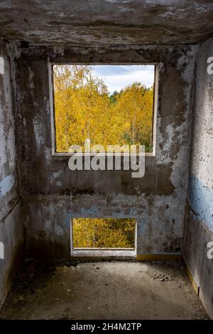 Blick durch das Loch für ein Fenster in einem beschädigten verlassenen Plattenhaus. Stockfoto