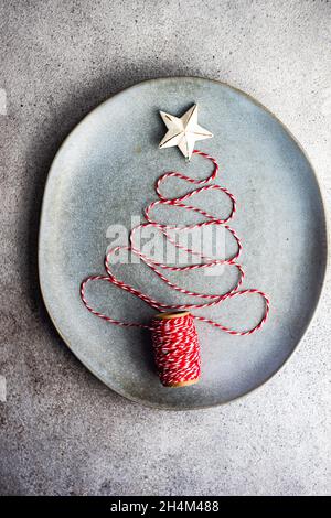 Platzeinstellung mit grauer Keramikplatte mit Weihnachtsbaum aus weißem und rotem Seil Stockfoto