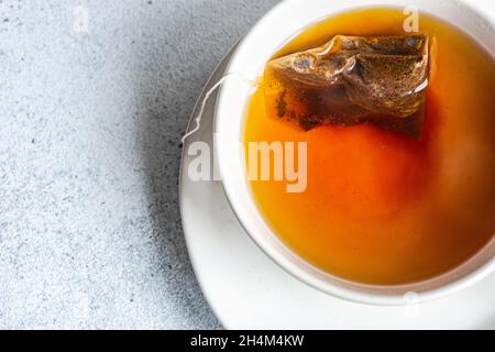 Tasse heißen schwarzen Tee mit Teebeutel auf weißem Beton Hintergrund Stockfoto