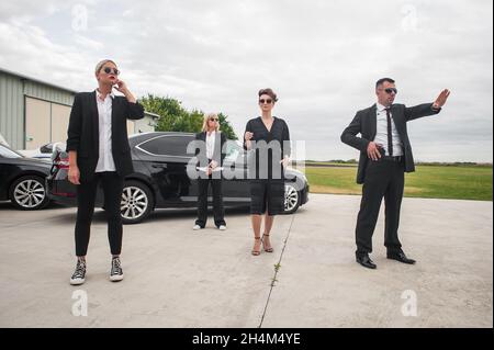 Ein professionelles Team von weiblichen und männlichen Leibwächtern schützt die berühmte prominente Person der Öffentlichkeit. Schließen Sie den Sicherheitsschutz. Polizeiagent in Zivil-Schwarz Stockfoto