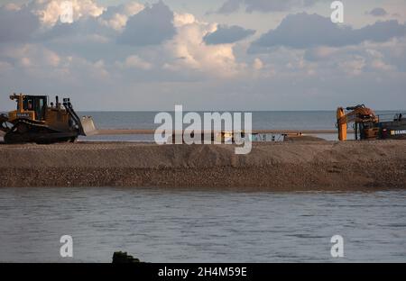 Pagham, Großbritannien. November 2021. Schwere Maschinen sahen Graben auf Pagham Schindelspieß, die Schaffung eines Kanals, die angenommen wird, um die Erosion am Strand in Pagham zu reduzieren, bedrohen in der Nähe Grundstücke. Quelle: Joe Kuis / Alamy Reportage Stockfoto