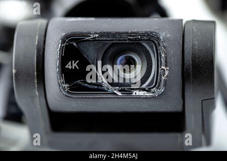 Makroaufnahme des 4k-Objektivs auf einer beschädigten Drohne nach einem Sturz mit defekten Kabeln, isoliert auf weißem Hintergrund. Stockfoto