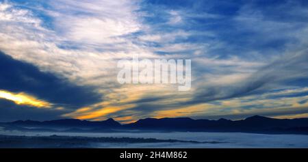 Helle Sonnenaufgang, der Nebel im Tal und Berge am Horizont. Breite Foto. Stockfoto