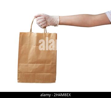 In der Hand des Kuriers in einem medizinischen Handschuh befindet sich ein Papierbeutel. Sichere Lieferung per Kurier zu Ihnen nach Hause, Quarantäne, sicher bleiben. Isoliert auf weißem Hintergrund. Stockfoto