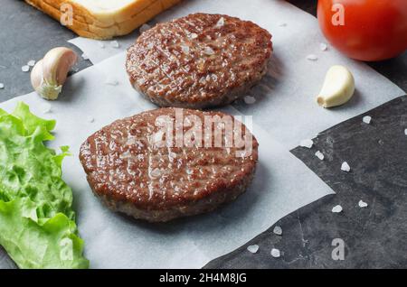 Hausgemachte Schnitzel für Burger mit Zutaten auf Papier Stockfoto