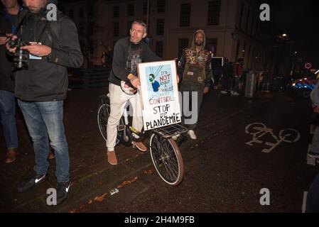 Den Haag, Niederlande. November 2021. Ein Protestler, der während der Demonstration mit einem Plakat auf seinem Fahrrad gesehen wurde.die Polizei verhaftete 13 Personen während einer Anti-Corona-Demonstration, als der scheidende niederländische Premierminister Mark Rutte neue Covid-19-Maßnahmen bekannt gab. Einige hundert Menschen versammelten sich vor dem ‘Ministerium für Justiz und Sicherheit' auf dem Turfmarkt, mit dem ohrenbetäubenden Geräusch von Pfeifen, Geschrei, Musik, dem Knallen von Kochtöpfen und Trommeln, gelegentlichen Feuerwerken und roten Fackeln. Kredit: SOPA Images Limited/Alamy Live Nachrichten Stockfoto