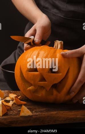 Hände schneiden, Kürbis zu Jack-o-Laternen für halloween schnitzen. Lächelnde halloween Kürbis Feiertagsdekoration. Stockfoto
