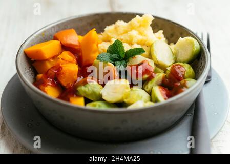 Hausgemachtes Gericht mit Winterkürbis, Rosenkohl, Kartoffelpüree und einer süßen und würzigen Sauce. Stockfoto