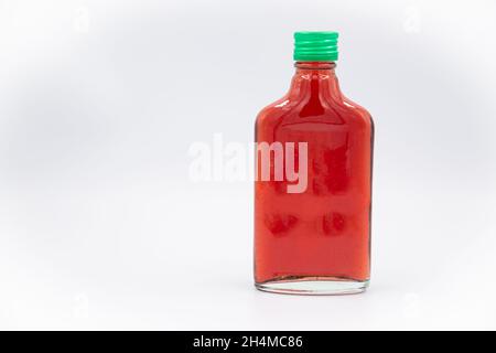 Eine Flasche Saft mit einem Getränk mit roter Johannisbeere und einem grünen Stopfen auf weißem Hintergrund Stockfoto